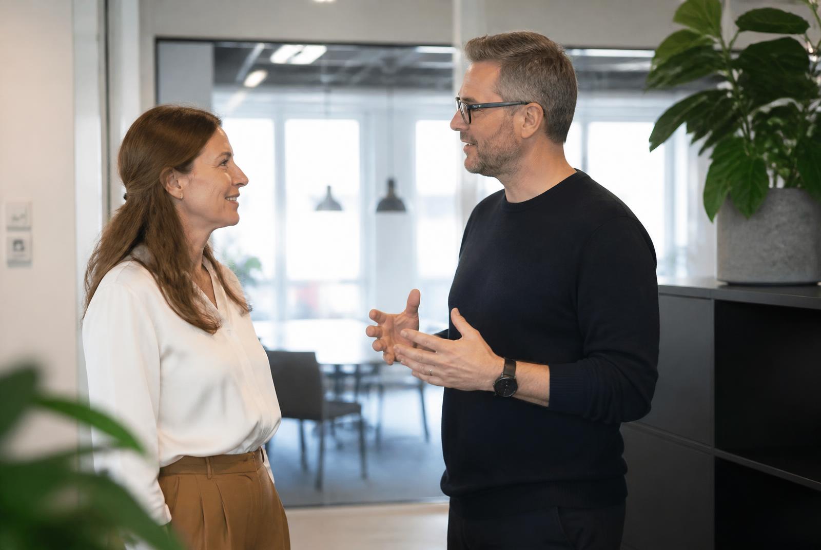 To kolleger i samtale på et lyst moderne kontor