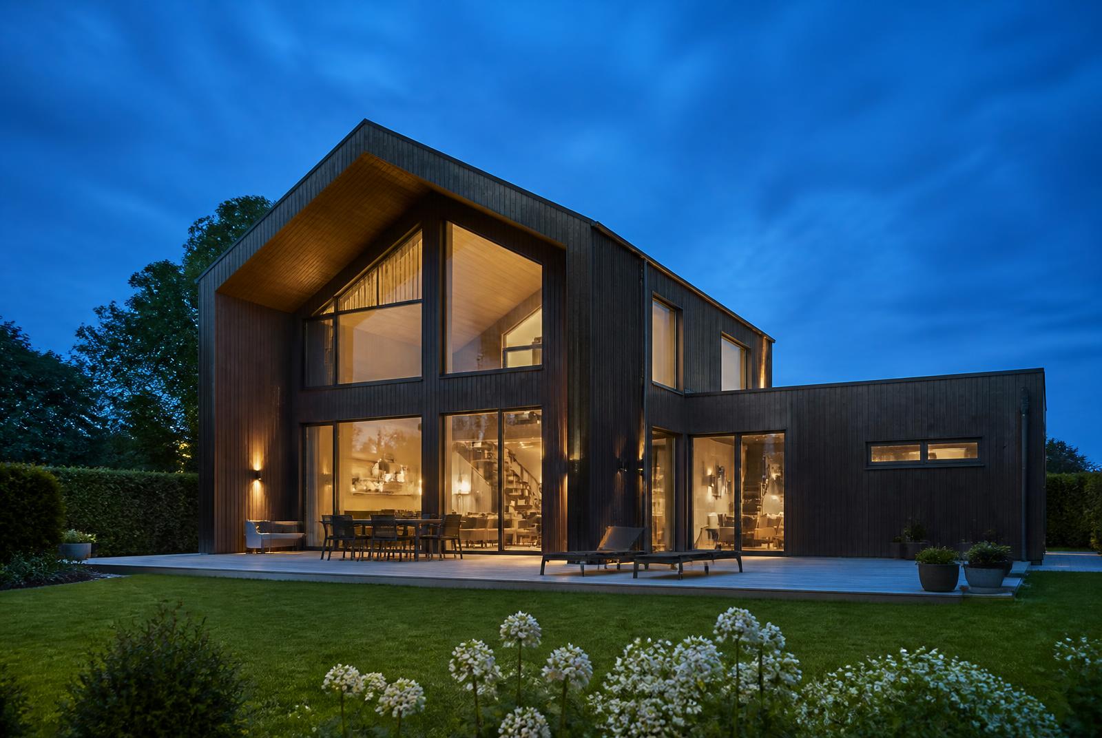 Moderne dansk villa med sort træbeklædning i blå time